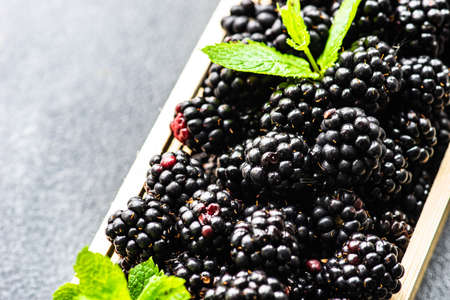 Organic food concept with fresh raw blackberries in wooden box on stone background with copy spaceの写真素材