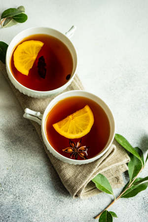 Mulled tea with lemon and spices on stone table with copy space