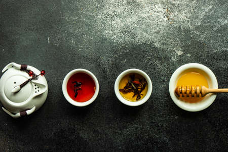 Floral tea concept with tea pot and cups on stone background with copy space