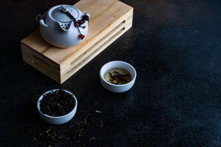 Floral tea concept with tea pot and cups on stone background with copy space