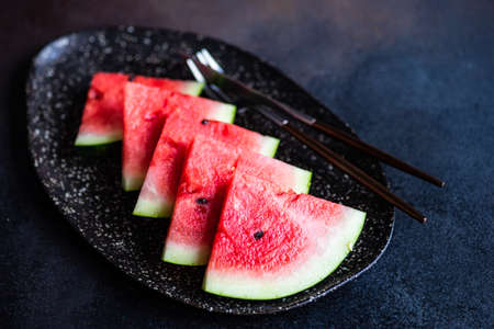 Organic watermelon slice on a plate served on stone background with copy spaceの写真素材