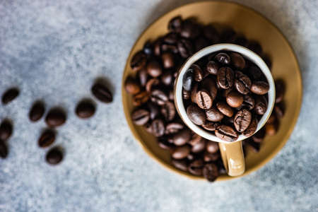 Cup full of organic coffee beans on stone background with copy spaceの写真素材