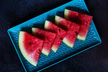 Organic watermelon slice on a plate served on stone background with copy spaceの写真素材