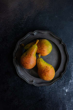 Organic food concept with ripe summer pears on dark stone background with copy spaceの写真素材
