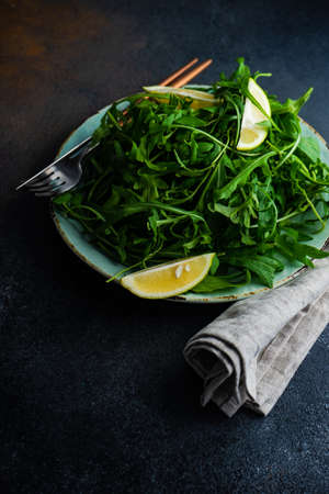 Healthy vegetable salad with organic rocket herb, lemon and flax seeds on stone backgroundの写真素材