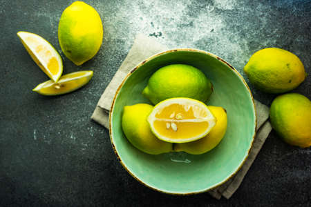 Organic lemons in a bowl on stone background with copy spaceの写真素材