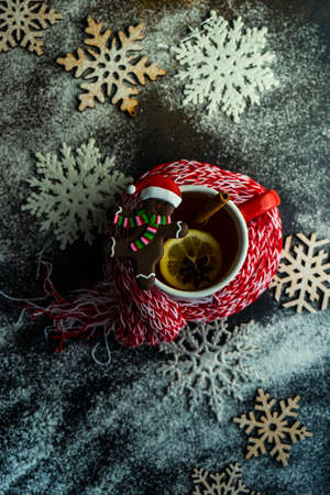 Cup of mulled tea with spices and lemon with red and white knitted scarf on stone background with copy spaceの写真素材