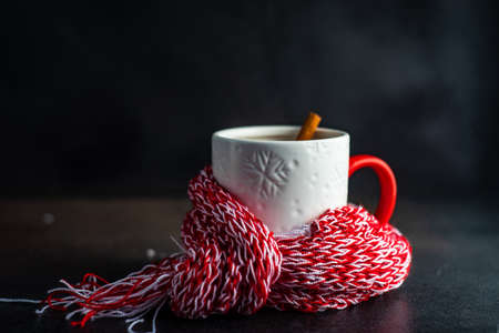 Cup of mulled tea with spices and lemon with red and white knitted scarf on stone background with copy spaceの写真素材