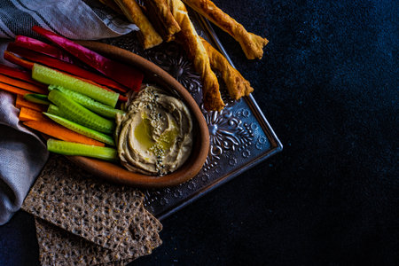 Traditional chickpeas hummus with olive oil and sesame seeds on stone background with copy space