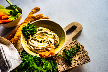 Traditional chickpeas hummus with olive oil and sesame seeds on stone background with copy space