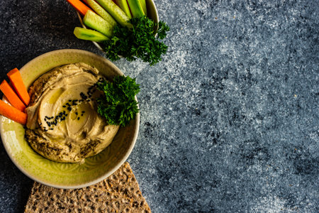 Traditional chickpeas hummus with olive oil and sesame seeds on stone background with copy space