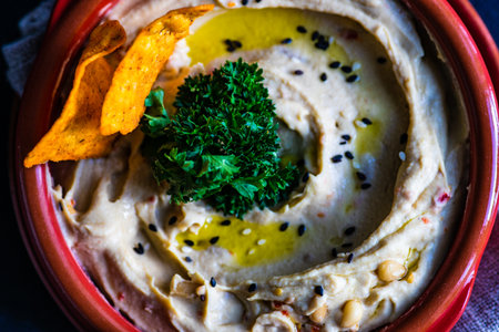 Traditional chickpeas hummus with olive oil and sesame seeds on stone background with copy space