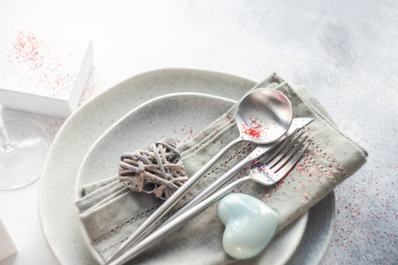 Table setting for holiday dinner in St. Valentine Day decorated with hearts on stone background with...