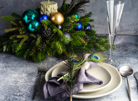Festive table setting decorated with peacock feather for Christmas dinner on stone background with copy spaceの写真素材