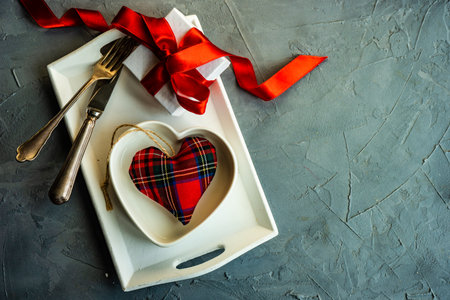 Festive table setting for St. Valentine day concept with hearts, cutlery and gifts on concrete background with copy spaceの写真素材