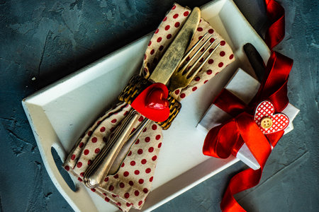 Festive table setting for St. Valentine day concept with hearts, cutlery and gifts on concrete background with copy spaceの写真素材