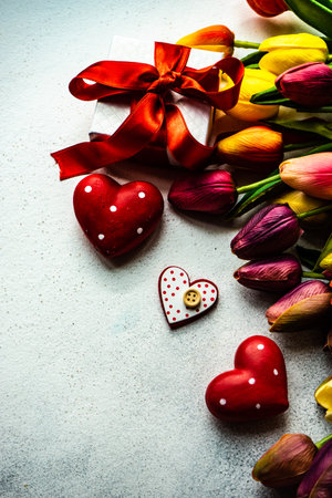 St. Valentine card concept with tulip flowers and gift on stone background with copy spaceの写真素材