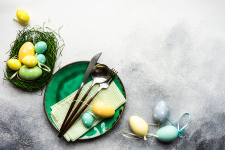 Table setting with eggs for festive holiday Easter dinner on rustic background with copy space