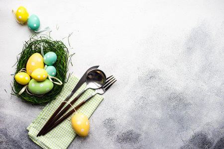 Table setting with eggs for festive holiday Easter dinner on rustic background with copy space