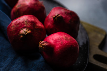 Ripe pomegranate on the vintage plate on stone table with copyspaceの写真素材