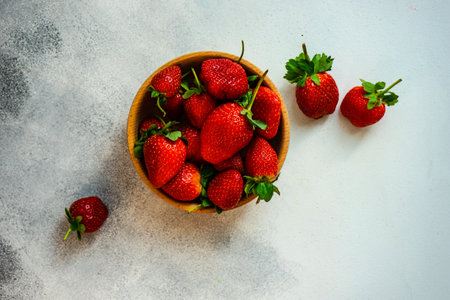 Organic summer berries in wooden bowl full of strawberries  on stone background with copy spaceの写真素材