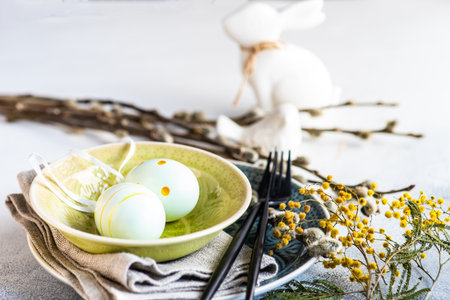 Holiday table setting for festive Easter dinner decorated with eggs