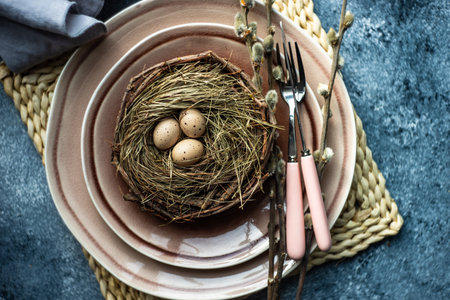 Festive holiday table setting for Easter dinner decorated with colored eggs on stone background with...