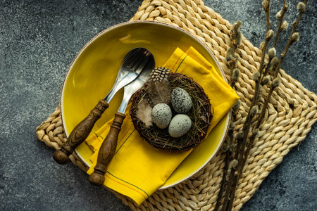 Festive holiday table setting for Easter dinner decorated with colored eggs on stone background with...