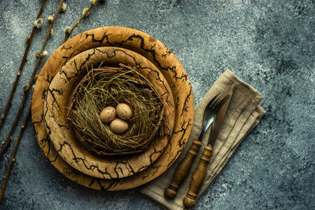 Festive holiday table setting for Easter dinner decorated with colored eggs on stone background with...