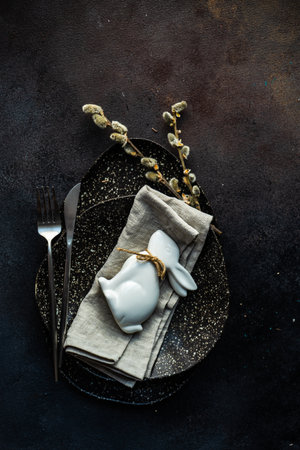 Easter festive table setting for holiday dinner on dark concrete background with copy space