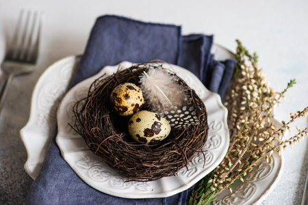 Festive table setting for holiday Easter dinner decorated with eggs and heather flowers on stone...