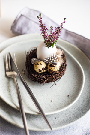 Festive table setting for holiday Easter dinner decorated with eggs and heather flowers on stone...