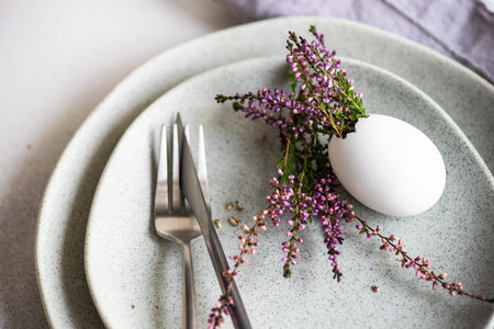 Festive table setting for holiday Easter dinner decorated with eggs and heather flowers on stone...