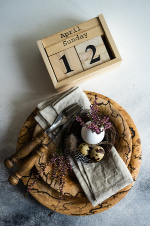 Festive table setting for holiday Easter dinner decorated with eggs and heather flowers on stone...