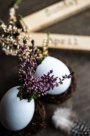 Easter holiday card concept with eggs and heather flowers on wooden background with copy spaceの写真素材