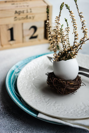 Festive table setting for holiday Easter dinner decorated with eggs and heather flowers on stone...