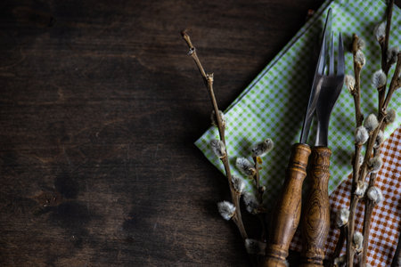 Easter table setting with willow and vintage cutlery set on wooden background with copy space