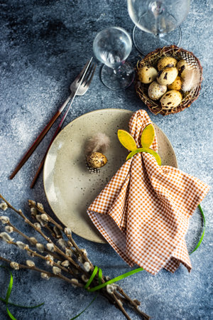 Holiday table setting for festive Easter dinner decorated with eggs on stone background with copy...