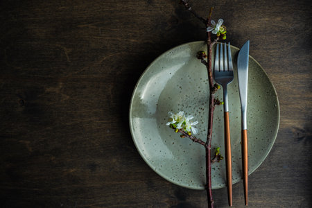 Spring table setting with cutlery and blooming cherry branch on rustic background with copy spaceの写真素材