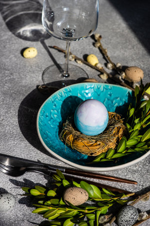 Holiday table setting for festive Easter dinner decorated with eggs on stone background with copy...