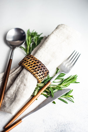 Minimalistic cutlery setting with rosemary herb on concrete background with copy spaceの写真素材