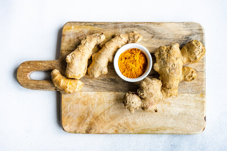 Ingredients for energy drink helping stay healthy with ginger roots on wooden board