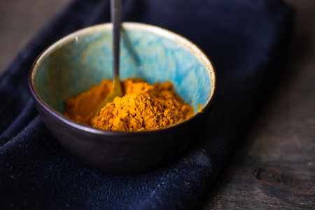 Organic food concept with turmeric spice in ceramic bowl on wooden table with copy spaceの写真素材