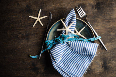 Summer table setting with plates and cutlery decorated with sea stars and shells on stone background with copy spaceの写真素材
