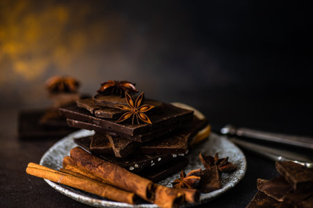 Chocolate bars, cinnamon and anise star spices on stone background with copy spaceの写真素材