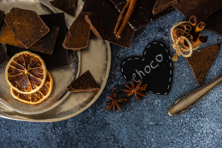 Chocolate bars, cinnamon and anise star spices on stone background with copy space