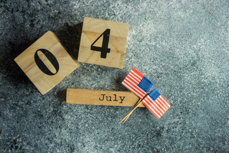 4th July celebration card concept with wooden calendar and USA flags on grey background with copy...