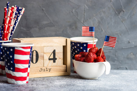 4th July celebration card concept with fresh strawberries and festive stuff on grey background with copy space