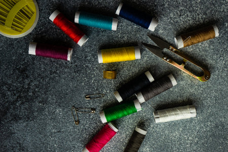 Sewing set concept with needles, spools and tools for crafting on grey concrete background with copy...