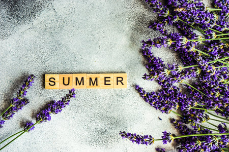 Summer card concept with frame made with fresh Lavandula flowers and wooden blocks on concrete background with copy spaceの写真素材